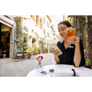 A woman using phone while sitting with a wine at restaurant