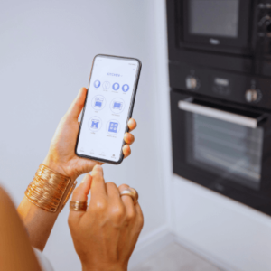 Person using smartphone to control smart kitchen appliances