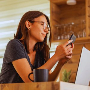 Woman using smart phone while working remotely at home