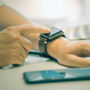 Businessman touching his smartwatch beside his phone while working at the office
