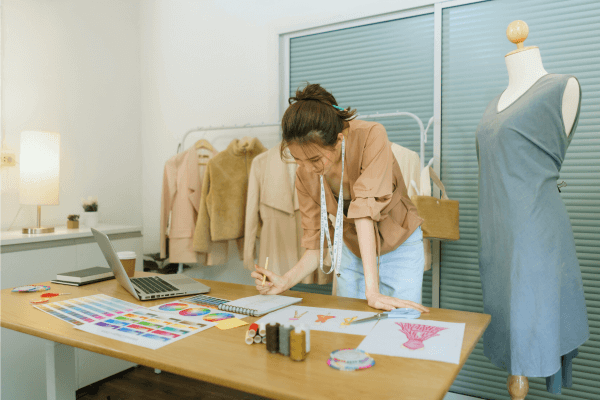 A fashion designer sketching her design on her table