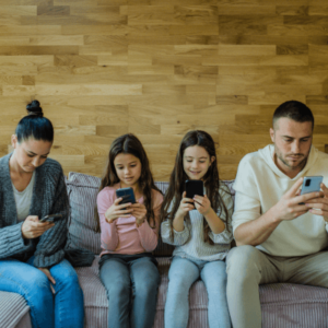 A group of family members on a living room using their mobile phones