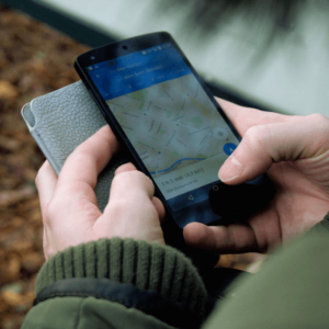 A person holding a smartphone and using a navigation app for location tracking