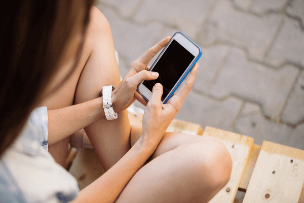 Charming girl sitting on a pallet using smart phone