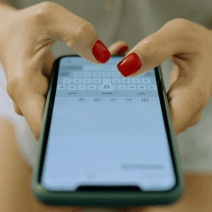 Hands of a Woman With Red Nails Typing on a Smartphone