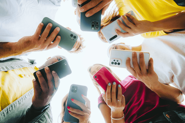 Teens in circle holding smart mobile phones