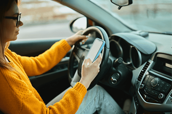 Young woman driver using mobile phone while driving car