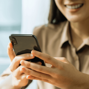 Smiling young woman hand holding smartphone