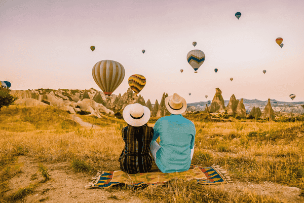 Happy Young Couple during Sunrise Watching the Hot Air Balloons of Kapadokya Cappadocia Turkey