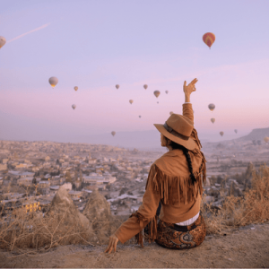 Woman Sitting and Waving Hand to Hot Air Balloons