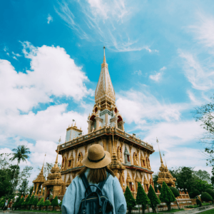 Young woman traveler with backpack traveling into beautiful pagoda in Wat Chalong