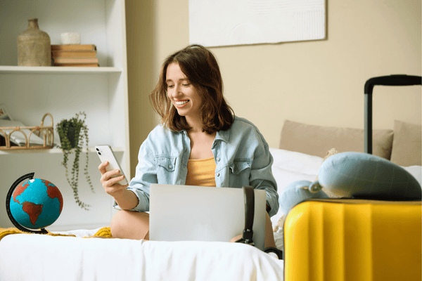 Female Traveler Using Mobile Phone in Bedroom. Itinerary Concept