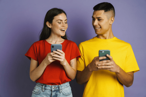 Happy Beautiful Couple Smiling While Using Mobile Phones