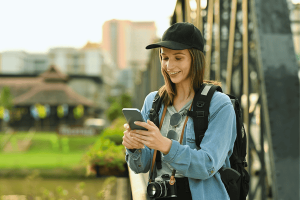 Portrait of hipster woman traveler using mobile phone