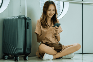 Traveler using her smartphone to check flight while sitting with