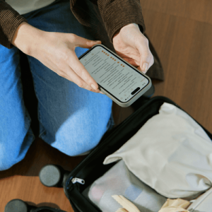 Woman Packing Suitcase While Using Mobile Phone