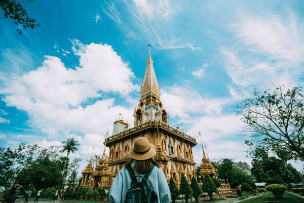 Young woman traveler with backpack traveling into beautiful pagoda in Wat Chalong