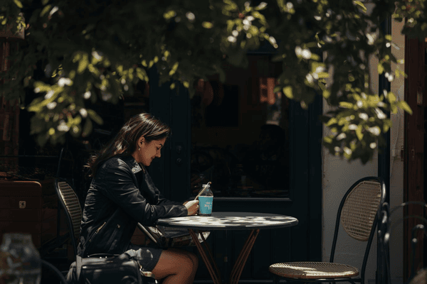 a traveler sitting on a nearby cafe using a smartphone
