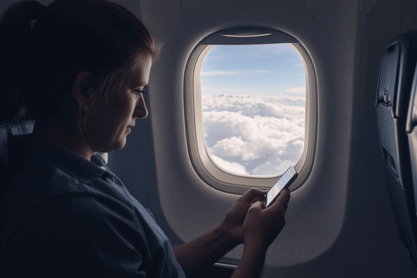 a traveler riding on a plane using a smartphone