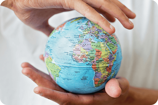 Two hands gently cradle a globe, showcasing continents and oceans, symbolizing care for the Earth