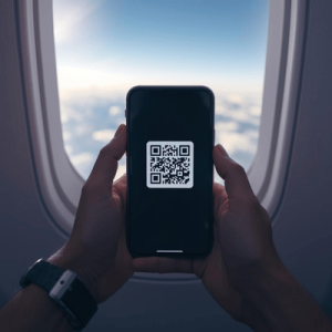 Close-up of a person activating a digital SIM by scanning a QR code on their phone while on a plane
