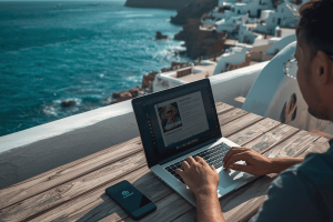 Digital nomad working on a laptop in a coastal Mediterranean town, representing the freedom of using Nomad eSIM for remote work